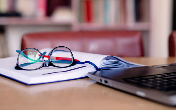 glasses sitting on top of books in front of a laptop